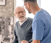 old-man-standing-by-table-supported-by-nurse 2